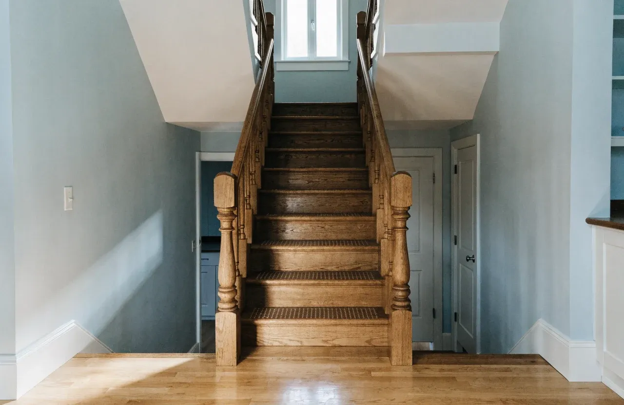 A wooden staircase inside a home with handrails on both sides